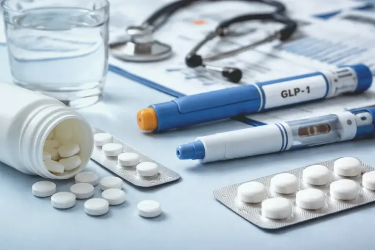 Tablets and an injection pen on an outdoor garden table beside a glass of water