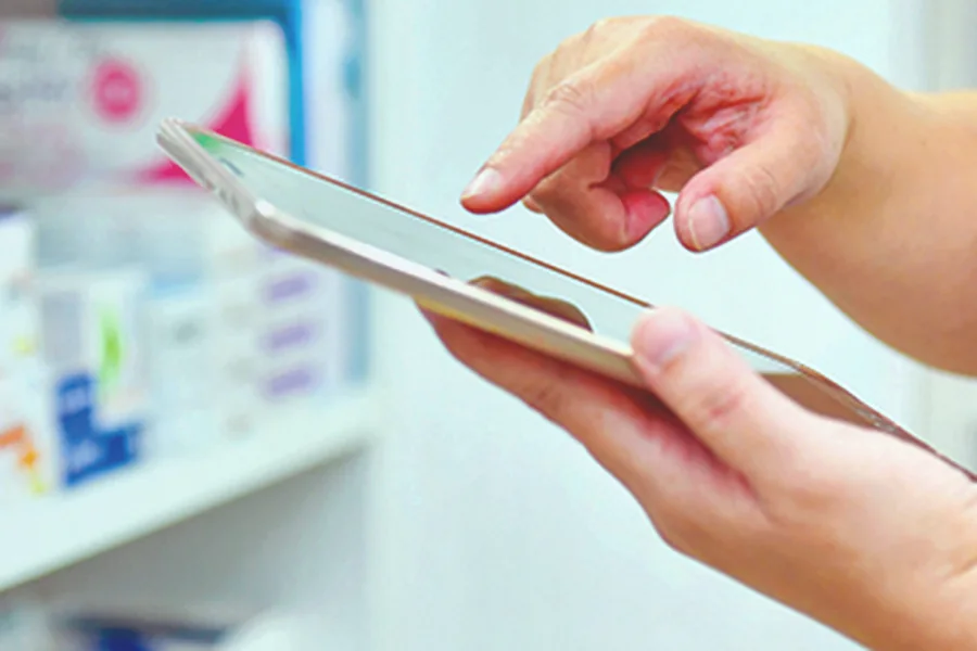 Person reviewing GLP-1 tablet status on a phone beside a glass of water and tablet blister pack